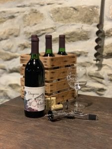 bottle of red wine called "Dangerous" with a few empty wine glasses and wine bottle corks on the table next to the bottle